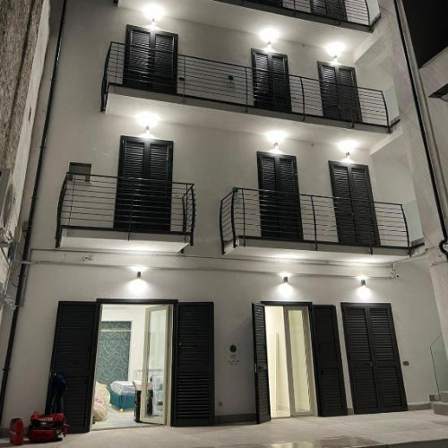Façade de l’Airport Capodichino Home à Naples avec balcons modernes et éclairage nocturne.