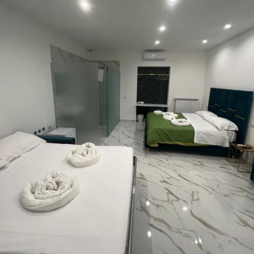 Chambre familiale de l’Airport Capodichino Home à Naples avec lits doubles et salle de bain moderne.