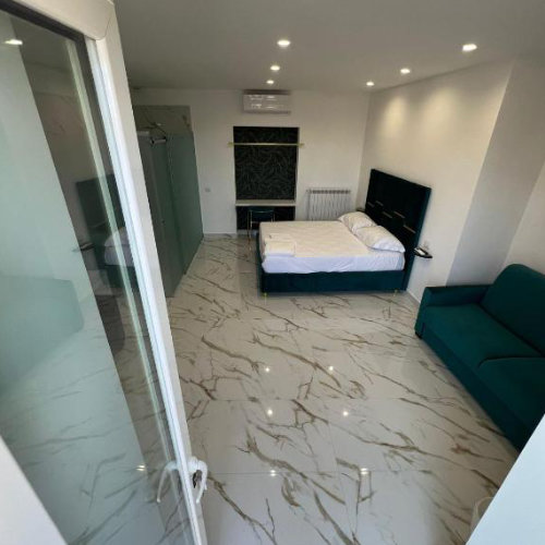 Chambre de l’Airport Capodichino Home à Naples avec lit double, canapé et intérieur contemporain.