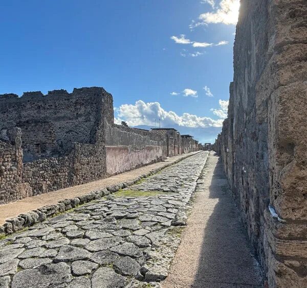 Rue antique pavée de Pompéi avec ruines romaines et murs en pierre.