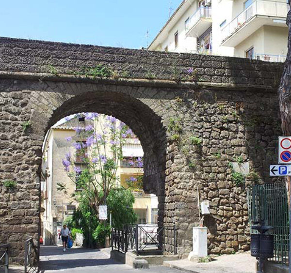 Anciens remparts de Sorrente avec arche en pierre et passage vers le centre historique.