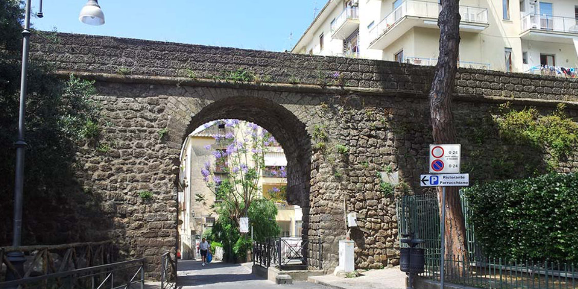 Anciens remparts de Sorrente avec arche en pierre et passage vers le centre historique.