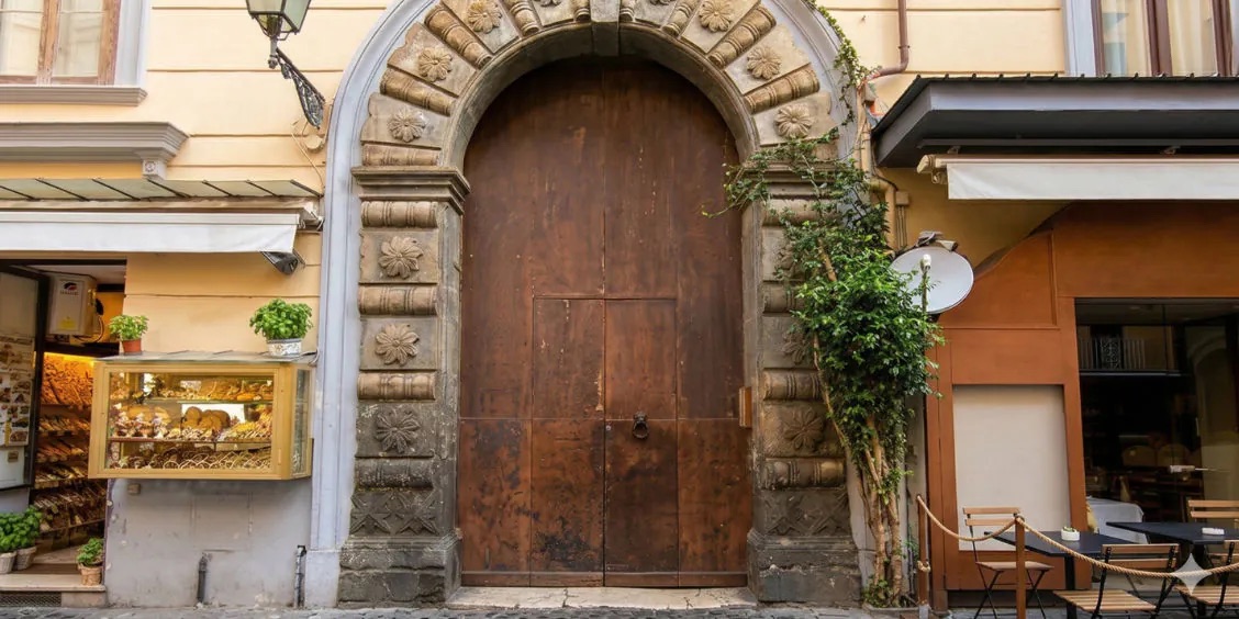 Ancien portail noble sur la via San Cesareo à Sorrente avec boutiques et façades historiques.
