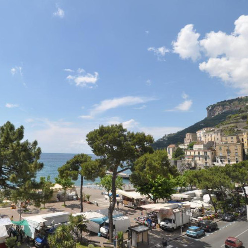 Vue panoramique du front de mer de Maiori avec ses pins, ses étals blancs et ses bâtiments accrochés aux falaises de la Côte Amalfitaine.