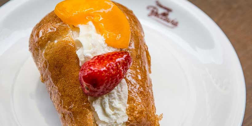 Baba napolitain imbibé au rhum garni de crème fouettée et fruits, spécialité pâtissière typique de Naples.