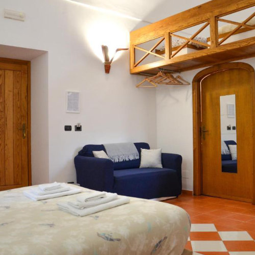 Chambre confortable avec lit, canapé bleu et mezzanine de rangement.