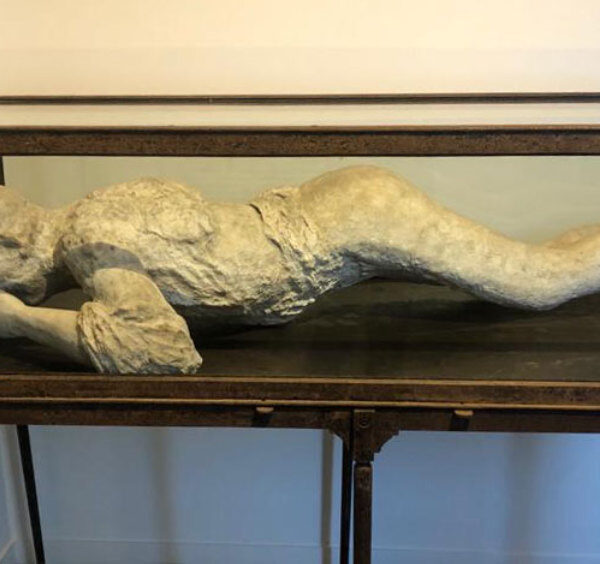 Moulage réaliste d'une victime de Pompéi dans sa vitrine de musée.
