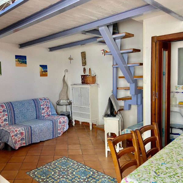 Espace de vie avec salon confortable et escalier coloré menant à la mezzanine.