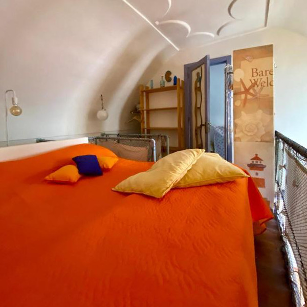 Chambre en mezzanine avec lit double sous un plafond voûté typique de l'architecture locale.