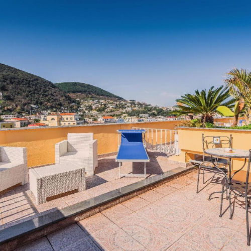 Solarium en terrasse avec mobilier de jardin et vue sur la ville et les collines.