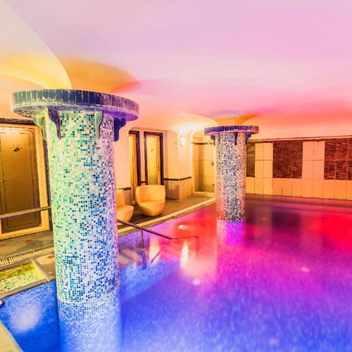 Espace bien-être avec piscine thermale intérieure et colonnes en mosaïque.