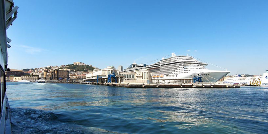 Port de Naples avec un grand navire de croisière amarré, vue sur la baie et la ville en arrière-plan.
