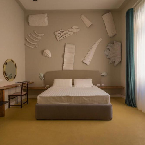 Chambre design avec sculptures murales blanches à l'Atelier Inès Arts Suites Naples.