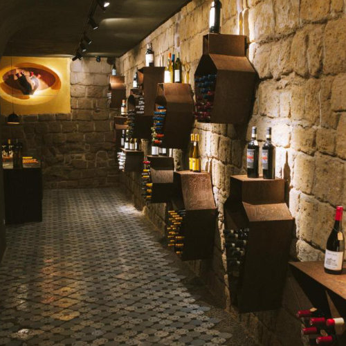 Cave à vin voûtée en pierre de tuf volcanique avec bouteilles de vin à Naples.