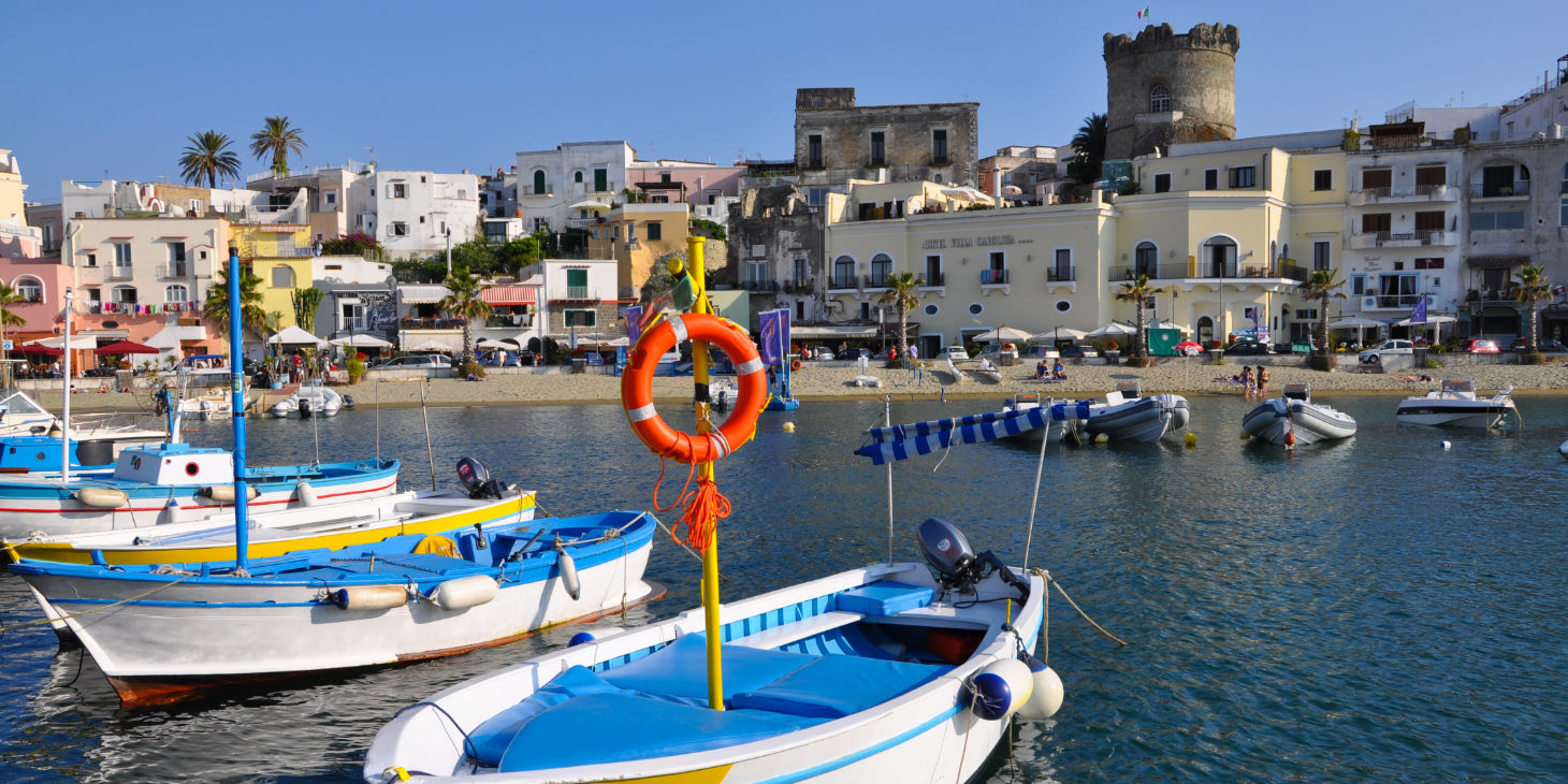 Bateaux de plaisance amarrés dans le port devant les maisons colorées d'Ischia.