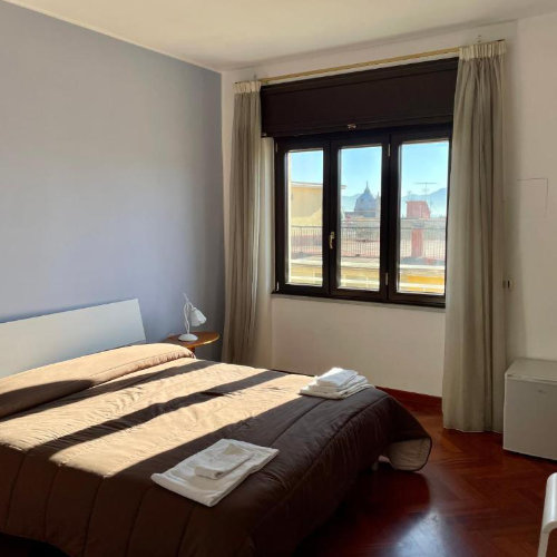 Chambre lumineuse à Naples avec lit double et vue sur les toits du centre historique.