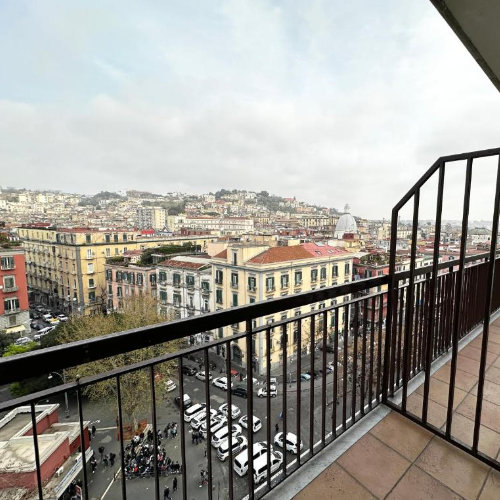 Balcon panoramique à Naples avec vue sur les immeubles et collines de la ville.