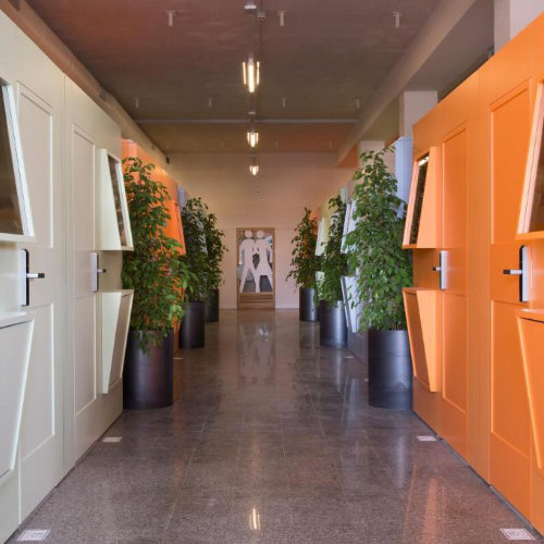 Couloir moderne d’hôtel à Naples avec cabines colorées et design minimaliste.