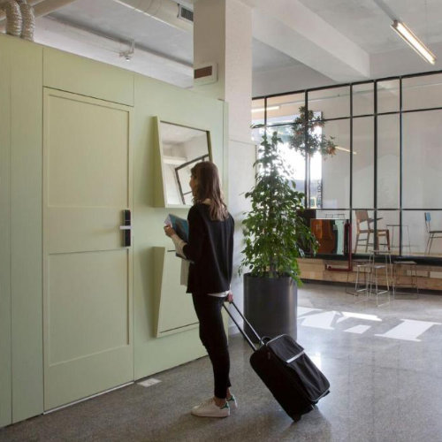 Voyageuse utilisant une cabine hôtel automatisée à Naples avec bagage à roulettes.
