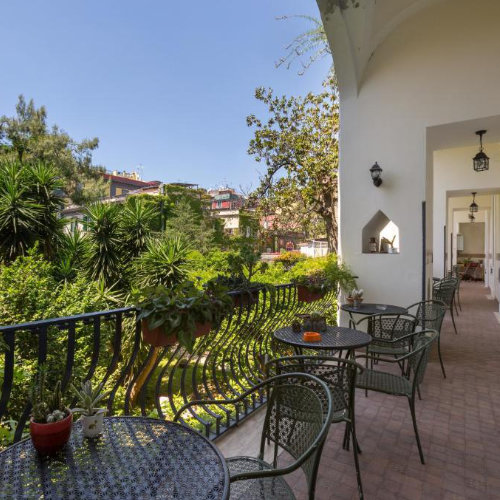 Terrasse verdoyante d’un hébergement à Naples avec tables, plantes et vue sur jardin.