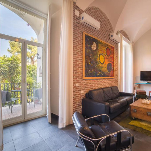 Salon élégant à Naples avec mur en briques, canapé et accès à une terrasse lumineuse.