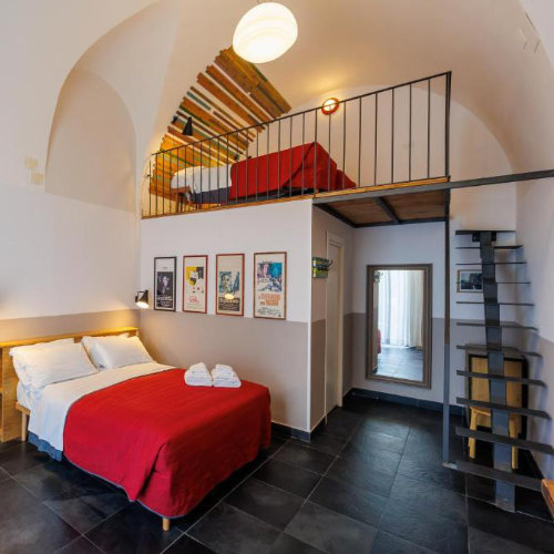 Chambre moderne en mezzanine à Naples avec lit double et espace design sous voûte.