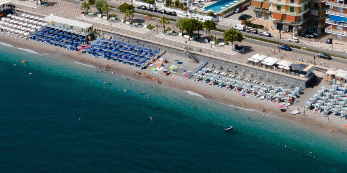 Vue aérienne de la grande plage de Maiori avec ses rangées de parasols bleus.