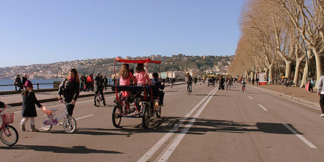 Promenade du bord de mer à Naples avec cyclistes, familles et vue sur la baie.