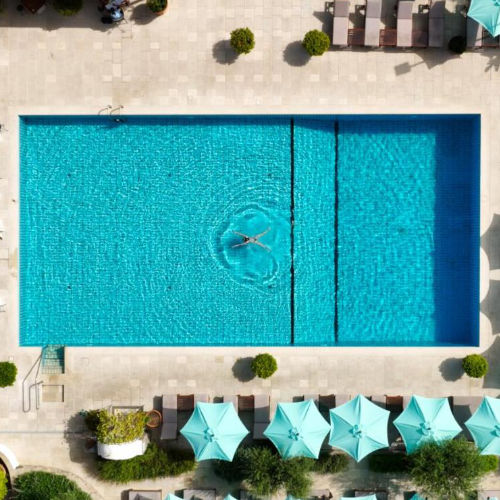 Vue plongeante sur la piscine et les parasols turquoise du Botania Relais & Spa.