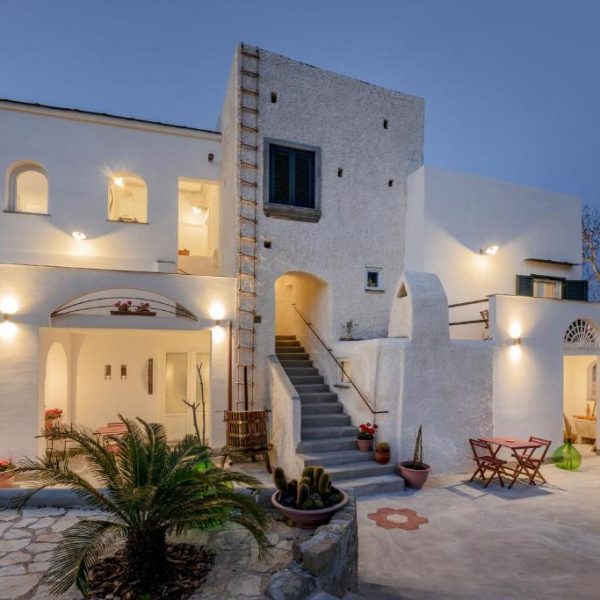 L'élégante façade nocturne et la cour éclairée du Grand Bleu B&B à Procida.