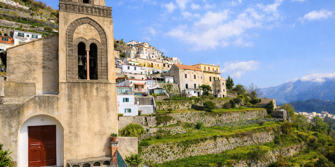 Clocher en pierre dominant le village de Scala et ses terrasses herbeuses face aux montagnes.
