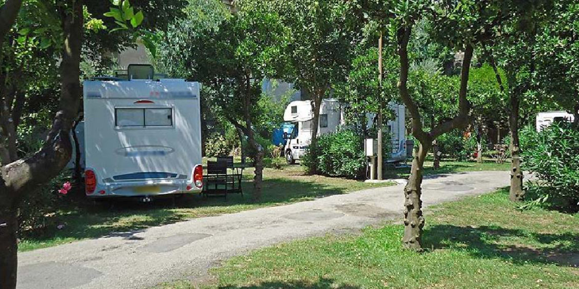 Camping-cars stationnés à l'ombre des arbres dans un camping à Pompéi.