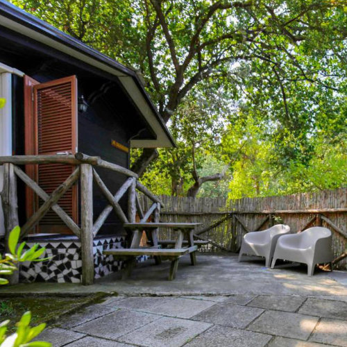 Bungalow du Camping Santa Fortunata à Sorrente avec terrasse ombragée sous les arbres.