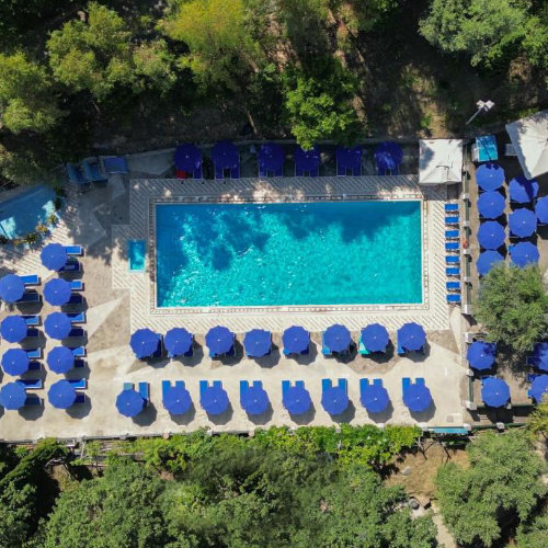 Piscine du Camping Santa Fortunata à Sorrente vue d’en haut avec transats et parasols bleus.