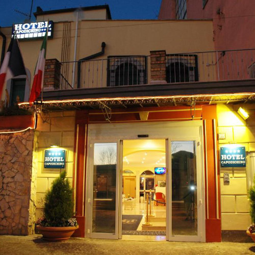 Entrée du Capodichino International Hotel à Naples avec façade illuminée et réception.