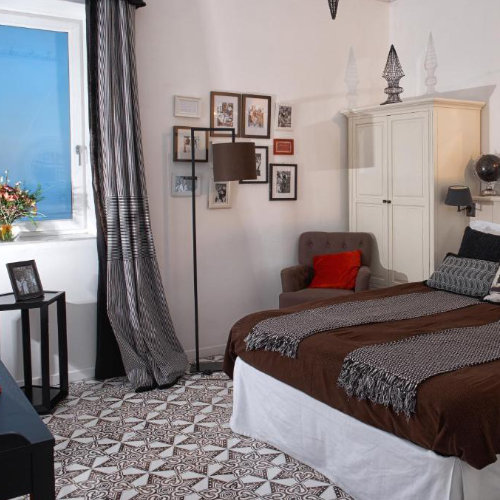 Chambre à Capri au sol carrelé géométrique, avec mur de cadres et mobilier élégant.