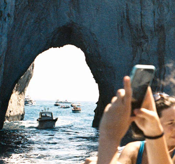 Tour en bateau en famille sous l'arche des Faraglioni à Capri.