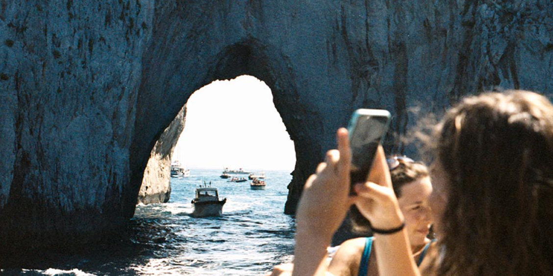 Tour en bateau en famille sous l'arche des Faraglioni à Capri.