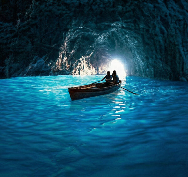Barque de touristes flottant sur l'eau bleu lumineuse à l'intérieur de la Grotte Bleue à Capri.