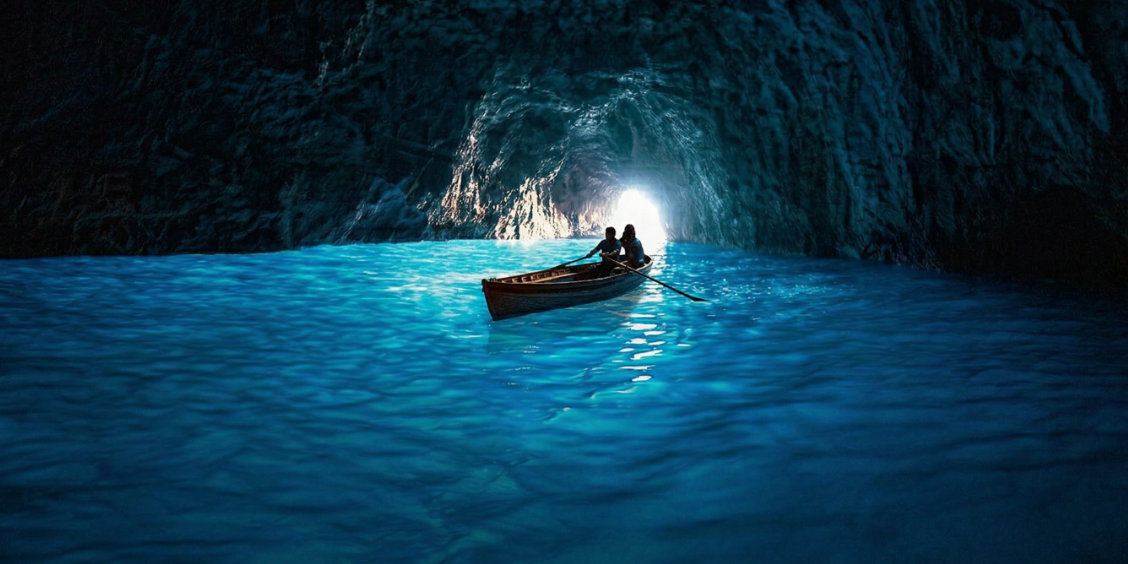 Barque de touristes flottant sur l'eau bleu lumineuse à l'intérieur de la Grotte Bleue à Capri.