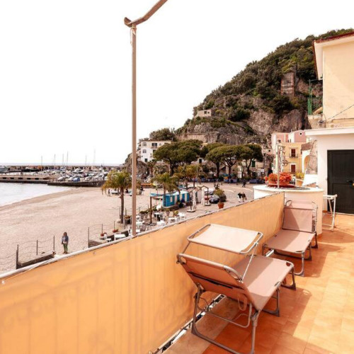 Terrasse de la Casa del Pozzo avec chaises longues et vue sur la plage et le port de Cetara.
