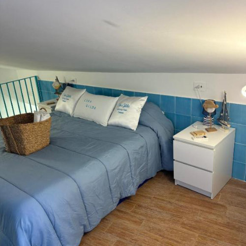 Chambre mansardée d’une maison de vacances à Sorrente avec lit bleu et décoration marine.