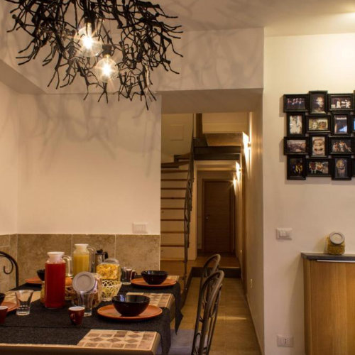 Salle à manger au design moderne avec un lustre artistique en branches et un mur décoré de cadres.