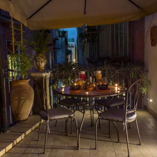 Terrasse romantique éclairée à la bougie avec vue sur les ruelles de Naples et plantes méditerranéennes.