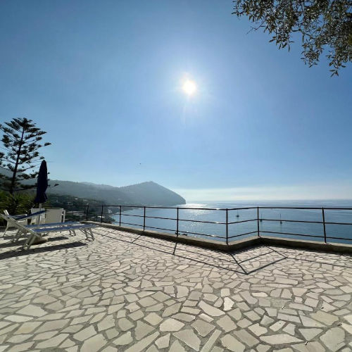 Grande terrasse panoramique ensoleillée avec chaises longues face à la baie.