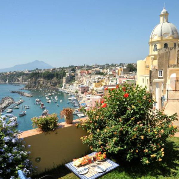 Terrasse fleurie avec vue panoramique sur Marina Corricella et le dôme de Procida.