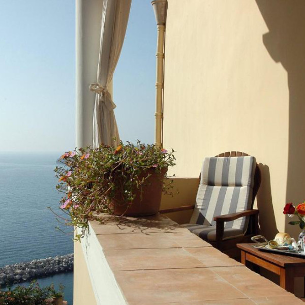 Coin détente sur un balcon ensoleillé face à la mer avec un petit-déjeuner typique.
