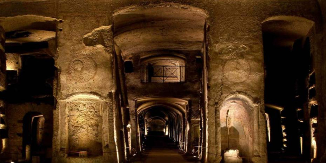 Intérieur des catacombes de San Gennaro à Naples, avec galeries souterraines voûtées, niches funéraires et éclairage tamisé.