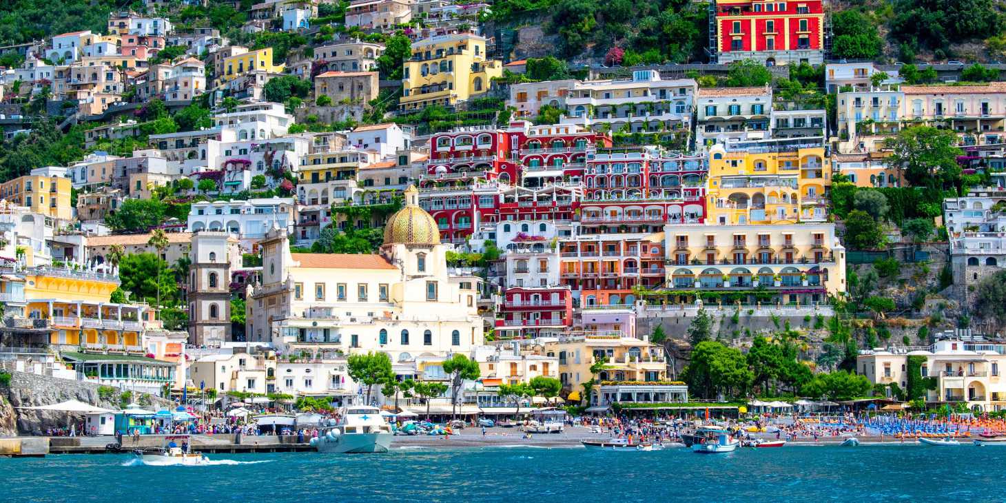 Centre de Positano vu depuis la mer avec l’église, les maisons colorées et la plage.