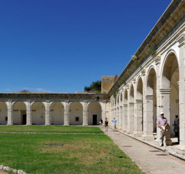 Grand cloître de la Chartreuse Saint-Jacques à Capri avec ses arches en pierre et sa pelouse centrale.